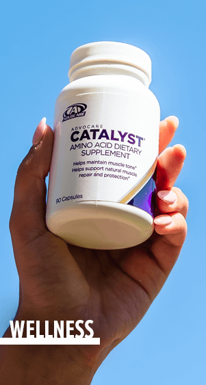 Wellness - a manicured hand holding up a bottle of AdvoCare Catalyst
