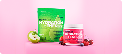 Hydration + Energy Green Apple Stick Pack & Mixed Berry Canister sitting around sliced fruit on a pink background.