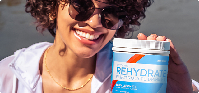 Woman smiling and holding a canister of Rehydrate Berry Lemon Ice