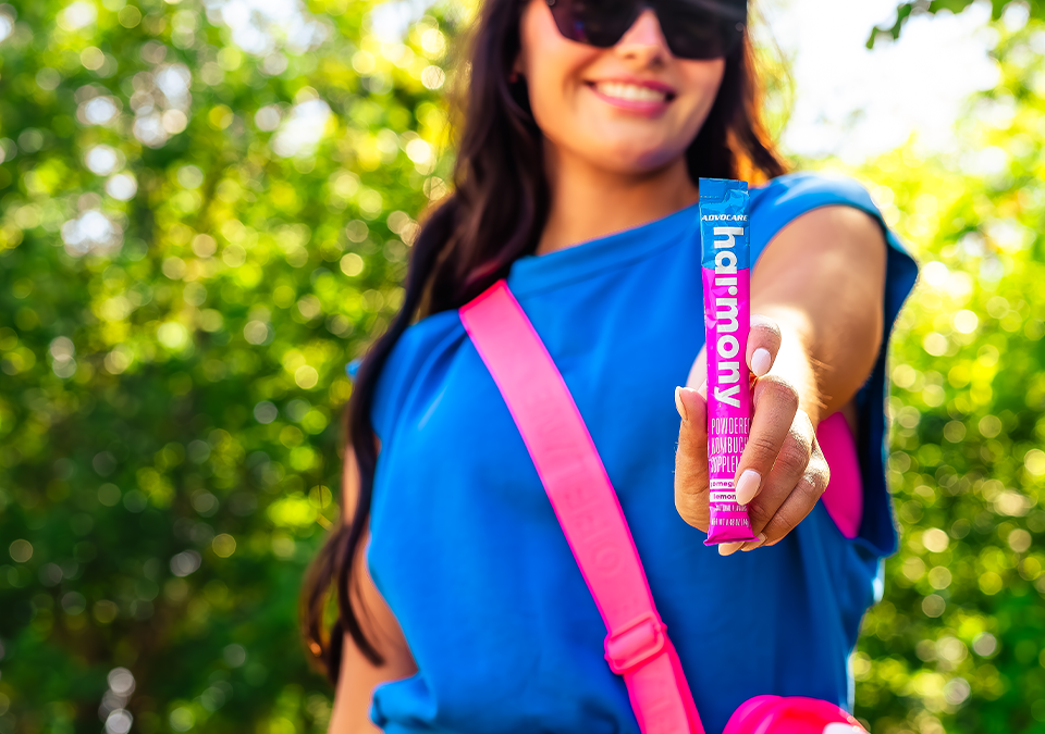 A young woman holding up a stick pack of Harmony