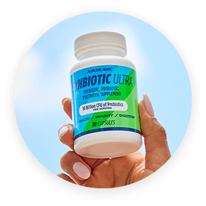 A hand holding a bottle of Synbiotic Ultra against a blue sky.