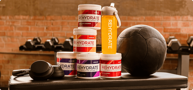 Rehydrate Canisters on a workout bench next to workout equipment and dumbbells.