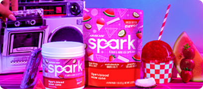 Spark Tiger's Blood canister and stick pack bags sitting next to a boombox, watermelon slice, coconut slice and a tiger's blood snowcone.