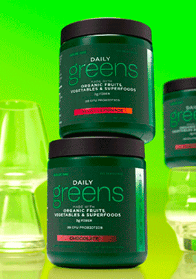 AdvoCare Daily Greens canisters stacked next to empty drinking glasses on a green backgorund.