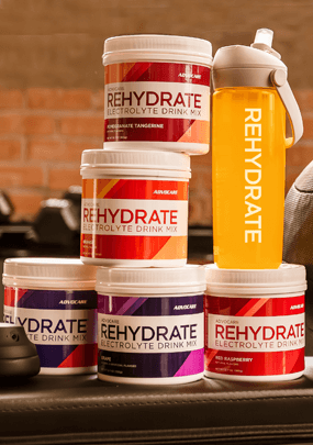 Rehydrate canisters stacked on a workout bench next to workout equipment in a gym.