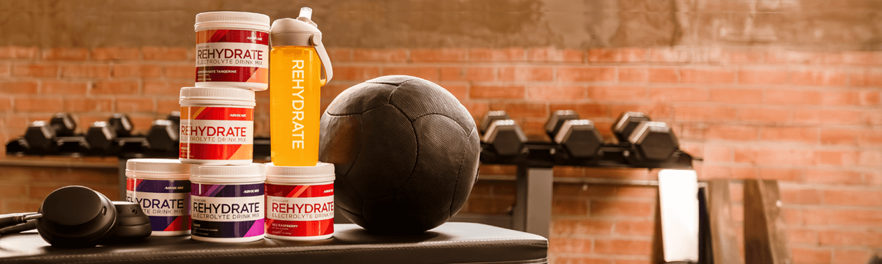 Rehydrate canisters stacked on a workout bench next to workout equipment.