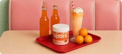 Spark Orange Cream Float canister on a diner tray next to oranges, orange soda and an orange cream float.